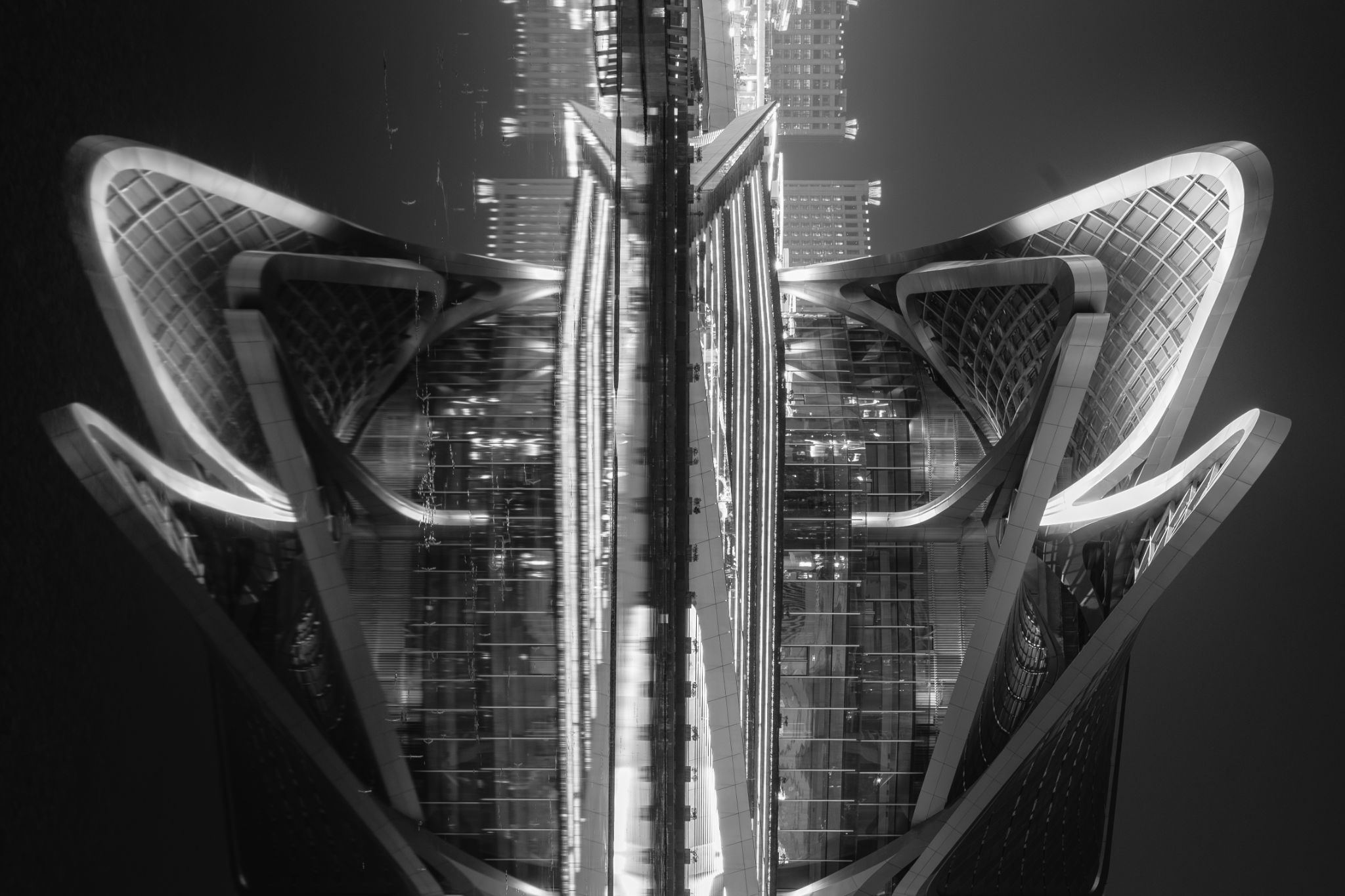 Gespiegelte Hochhausfassade bei Nacht, symmetrisch wie ein Flügelpaar