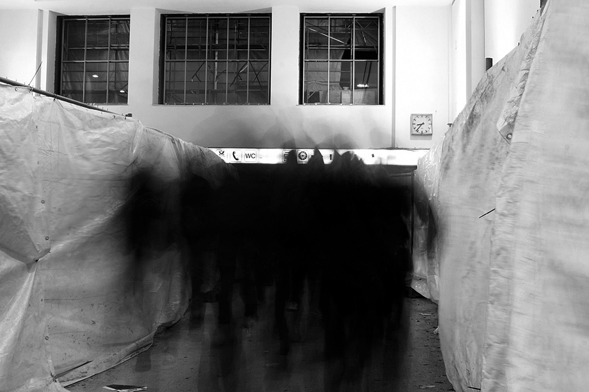 Verwischte Menschen in einer Halle vor verhüllten Wänden