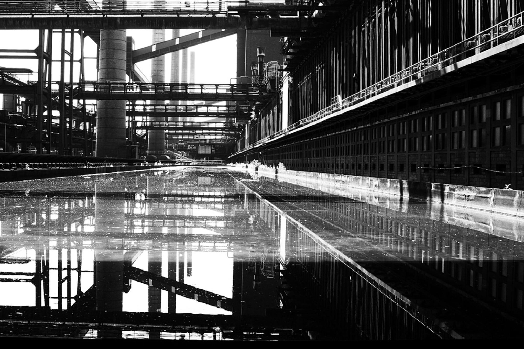 Industrieanlage mit Stahlgerüsten, im nassen Boden gespiegelt