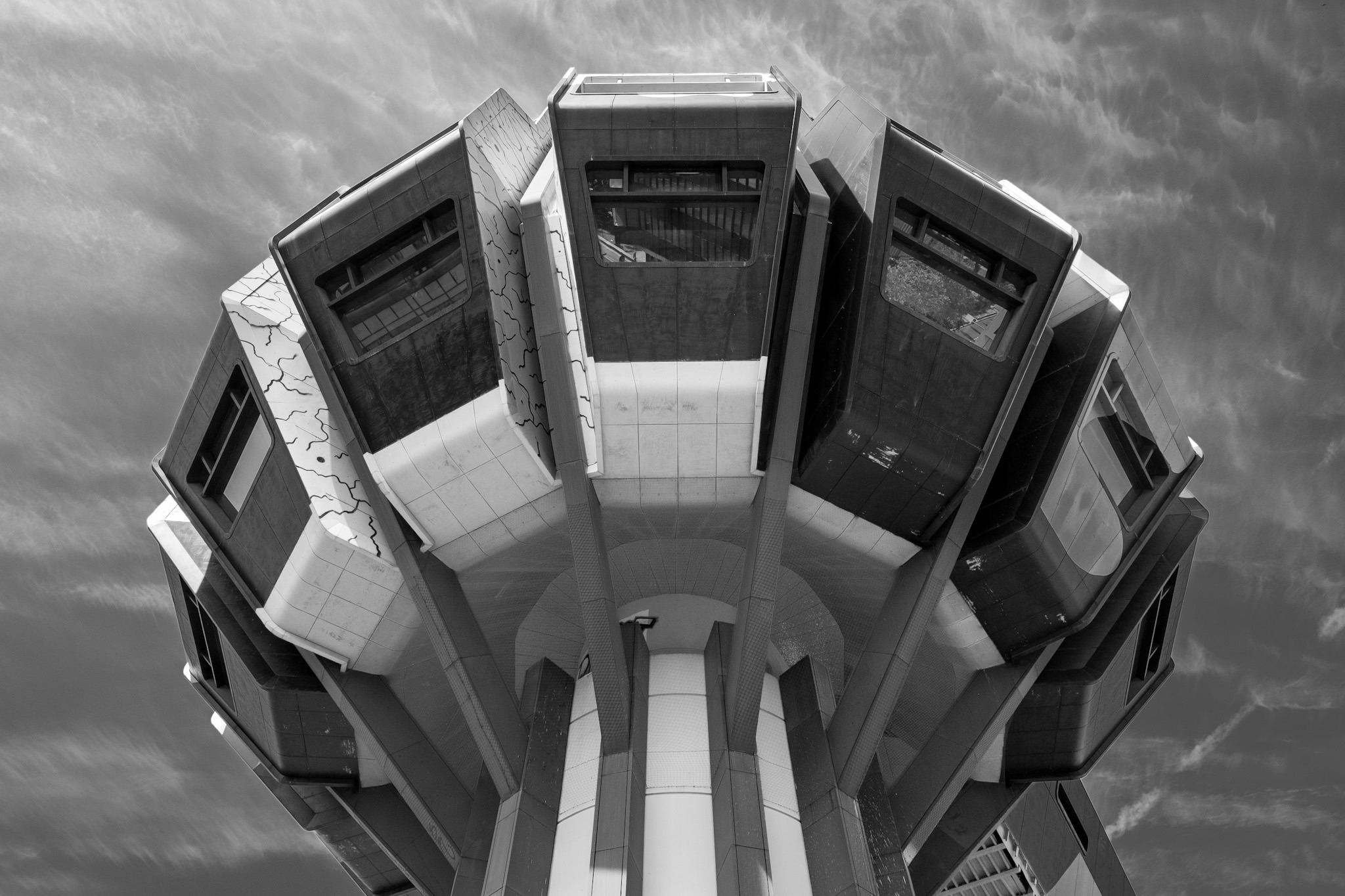 Futuristischer Turm mit sternförmig auskragenden Modulen vor Wolkenhimmel